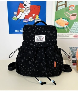 Detailed texture of black corduroy backpack with grey bow patterns and drawstring closure