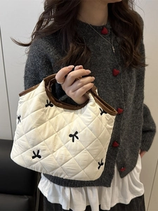Quilted white handbag with black bow embroidery and contrast brown leather handles