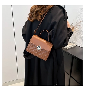 Detail of caramel brown quilted crossbody bag featuring a golden petal-shaped twist lock