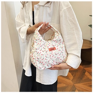 Close-up of cream floral tote bag with pink flowers and a stitched red brand label