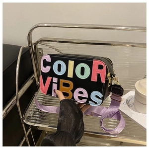 Dettaglio della borsa a tracolla nera con cinturino viola e scritte COLOR VIBES