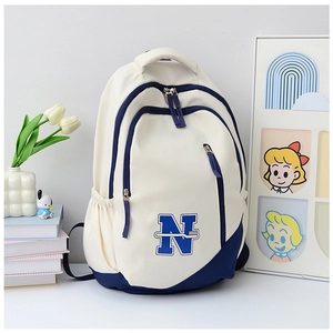Detail of canvas school backpack featuring large blue N letter and multi-compartment design
