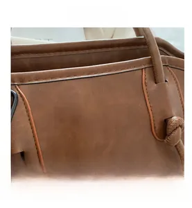 Detail of a brown tote bag featuring pebbled faux leather and knotted strap design