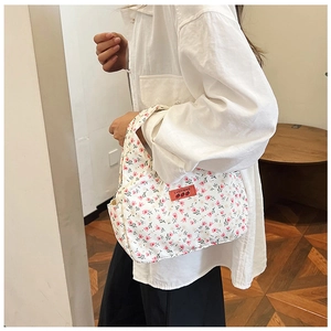 Detailed close-up of a white floral tote bag featuring pink tulips and a red logo patch