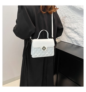 Detail of white quilted leather handbag with floral metal lock on a black coat model