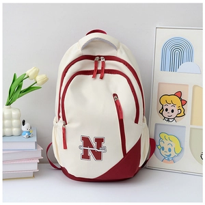 Close-up of cream and burgundy canvas backpack with letter N and toothbrush graphic