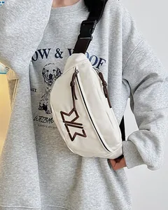 Close-up of white canvas chest bag with brown embroidered logo and adjustable strap