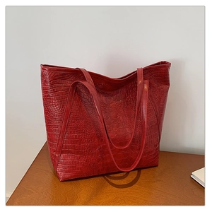 Detailed macro view of dark red crocodile embossed texture on a large tote bag
