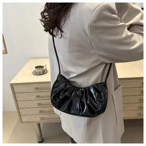 Détail du sac à bandoulière en croissant noir brillant avec texture plissée et fine lanière