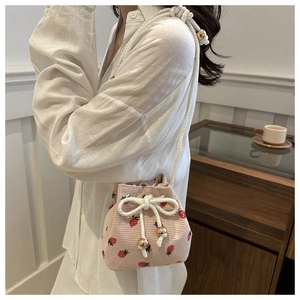 Pink corduroy bucket bag detail with red strawberry print and golden metal rope tips