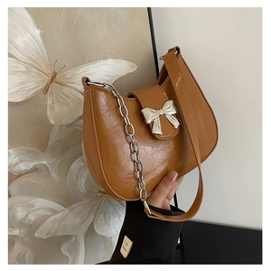 Detail of hobo bag featuring shiny brown wrinkled leather and a silver bow buckle