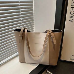 Detailed close-up of a color-block tote bag with adjustable brown leather shoulder straps