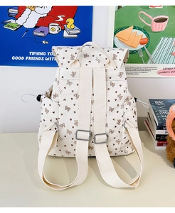 Detail view of corduroy backpack straps with metal buckles and heart pattern fabric