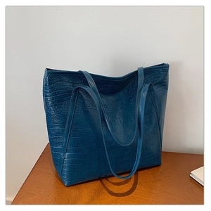 Macro detail of dark blue tote bag showing the embossed crocodile skin texture and leather finish
