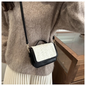 Close-up of black leather and white shearling flap bag with gold hardware and strap