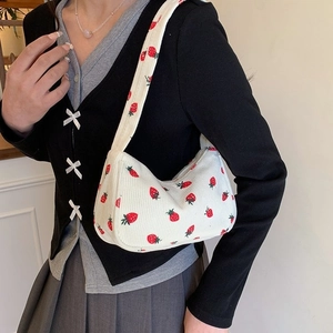 White corduroy underarm bag with strawberry prints worn by a model in casual style