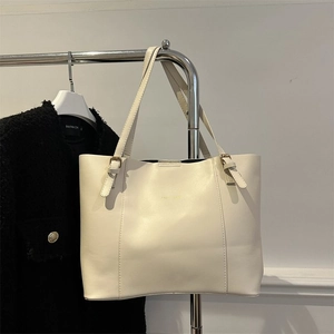 Detail view of cream oversized faux leather tote bag with elegant metallic buckle accents