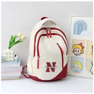 Close-up of stylish canvas backpack featuring beige and burgundy patchwork with a large N logo