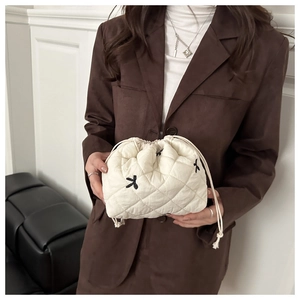 Close-up of quilted cream bucket bag with black star embroidery and drawstring closure
