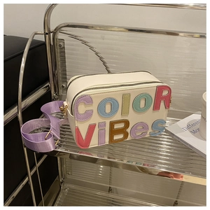 Dettaglio di una borsa bianca con lettere 3D colorate Color Vibes e doppia zip frontale