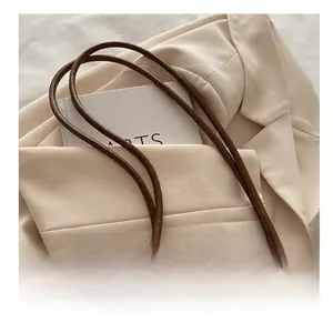 Detail of a dark brown leather tote bag with FASHION logo and slender shoulder straps