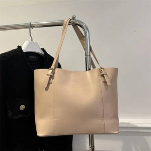 Detailed view of beige faux leather tote bag with thin adjustable straps and gold buckles