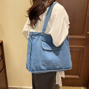 Light blue denim tote bag with front pocket and lace detail shown on a female model
