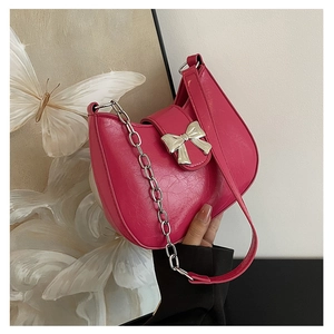 Close-up of pink crescent underarm bag with silver bow buckle and metallic chain strap