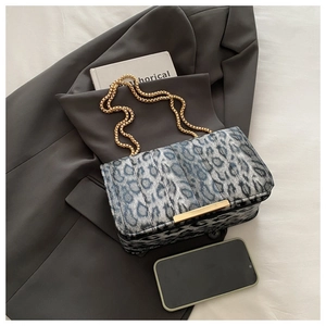 Détail du sac léopard avec fermoir doré et bandoulière chaîne sur un blazer gris