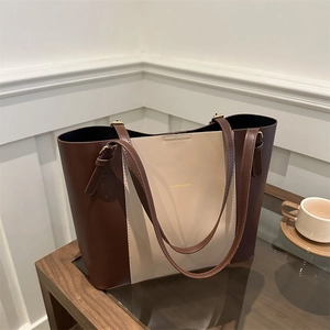 Detail of two-tone tote bag with gold lettering and adjustable leather straps