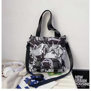 Close-up of black and white graffiti messenger bag with dual buckle closure and straps