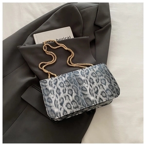 Détail du sac léopard avec motif matelassé et chaîne dorée sur un blazer gris