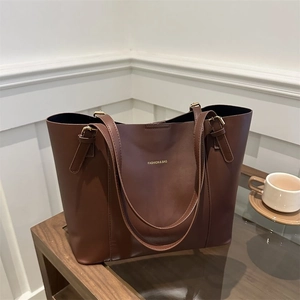 Macro shot of large brown leather tote bag with elegant gold hardware and embossed gold logo