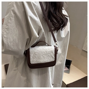 Detail shot of the brown leather and white faux fur texture on a compact crossbody handbag