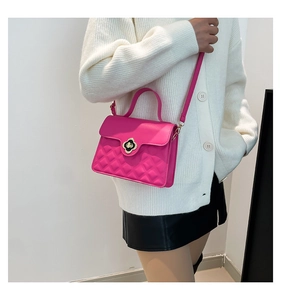 Detail of fuchsia crossbody bag showing quilted leather texture and clover-shaped gold lock