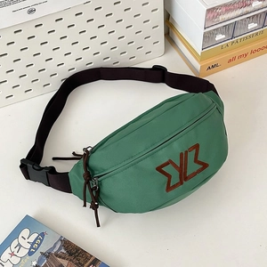 Detail of green crossbody bag showing secure plastic buckle and adjustable black strap