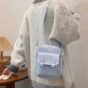 Minimalist light blue canvas crossbody bag with twin buttons in a cozy lifestyle setting