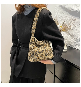Gros plan du sac seau en fausse fourrure léopard porté avec un manteau d'hiver noir élégant