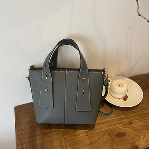 Minimalist grey leather bucket bag with pebble texture and white stitching details