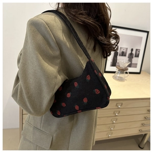 Détail du sac à bandoulière en velours côtelé noir avec broderie fraise rouge en intérieur