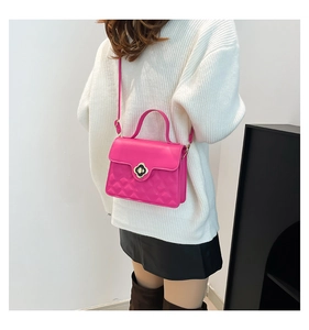 Detail of rose pink quilted crossbody bag with golden clover clasp worn by model