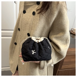 Close-up of black quilted drawstring bucket bag with elegant embroidery and woven rope handle