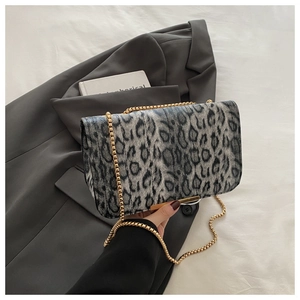Gros plan du sac léopard gris avec chaîne dorée posé sur une veste sombre