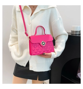 Model wearing a fuchsia quilted crossbody bag with a white sweater in a modern room