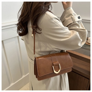 Détail d'un sac à bandoulière en cuir synthétique marron avec boucle métallique dorée en D
