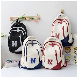 Lifestyle view of multi-compartment canvas school backpacks in various color block styles