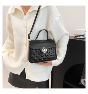 Chic black crossbody bag with quilted patterns and clover-shaped golden clasp on a model