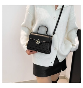 Close-up of black quilted shoulder bag with elegant golden floral metal clasp detail