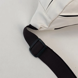 Detailed close-up of white nylon crossbody bag showing black zipper and adjustable strap
