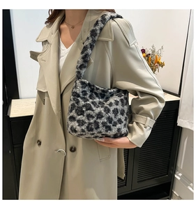 Détail du sac à épaule en peluche à motif léopard porté avec un long trench-coat chic